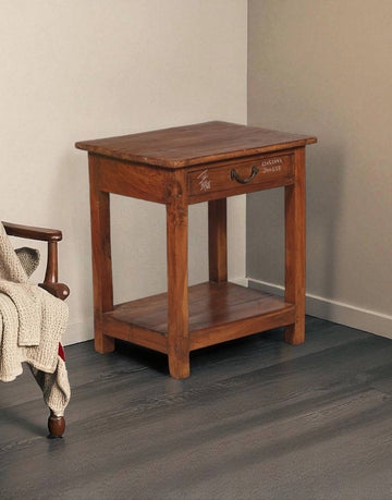 Wooden side table with a drawer next to a chair on a gray floor.