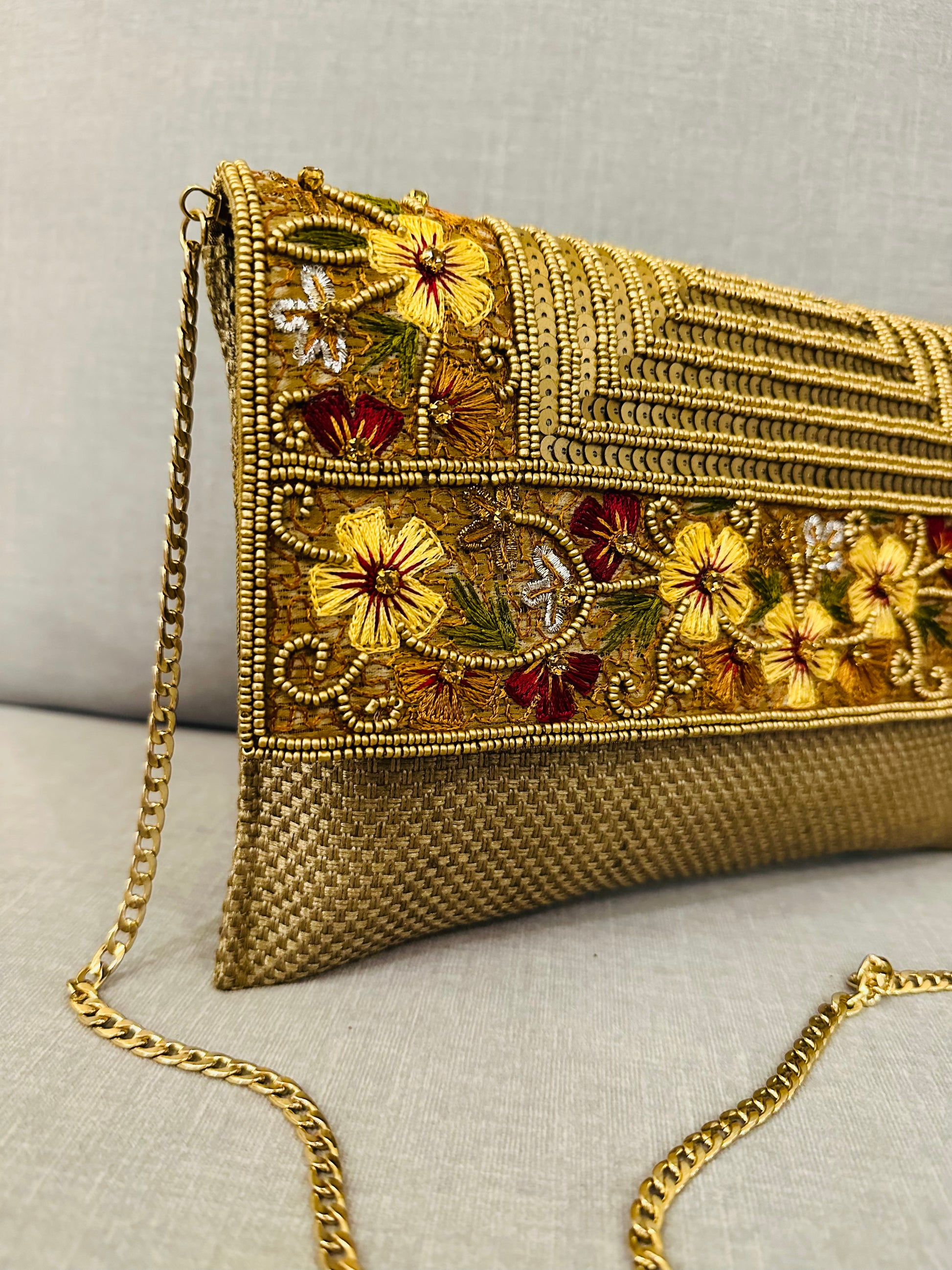Close-up of intricate zardozi embroidery work on jute fabric clutch showing gold thread and bead details