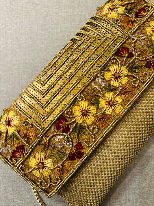 Close-up of intricate zardozi embroidery work on jute fabric clutch showing gold thread and bead details