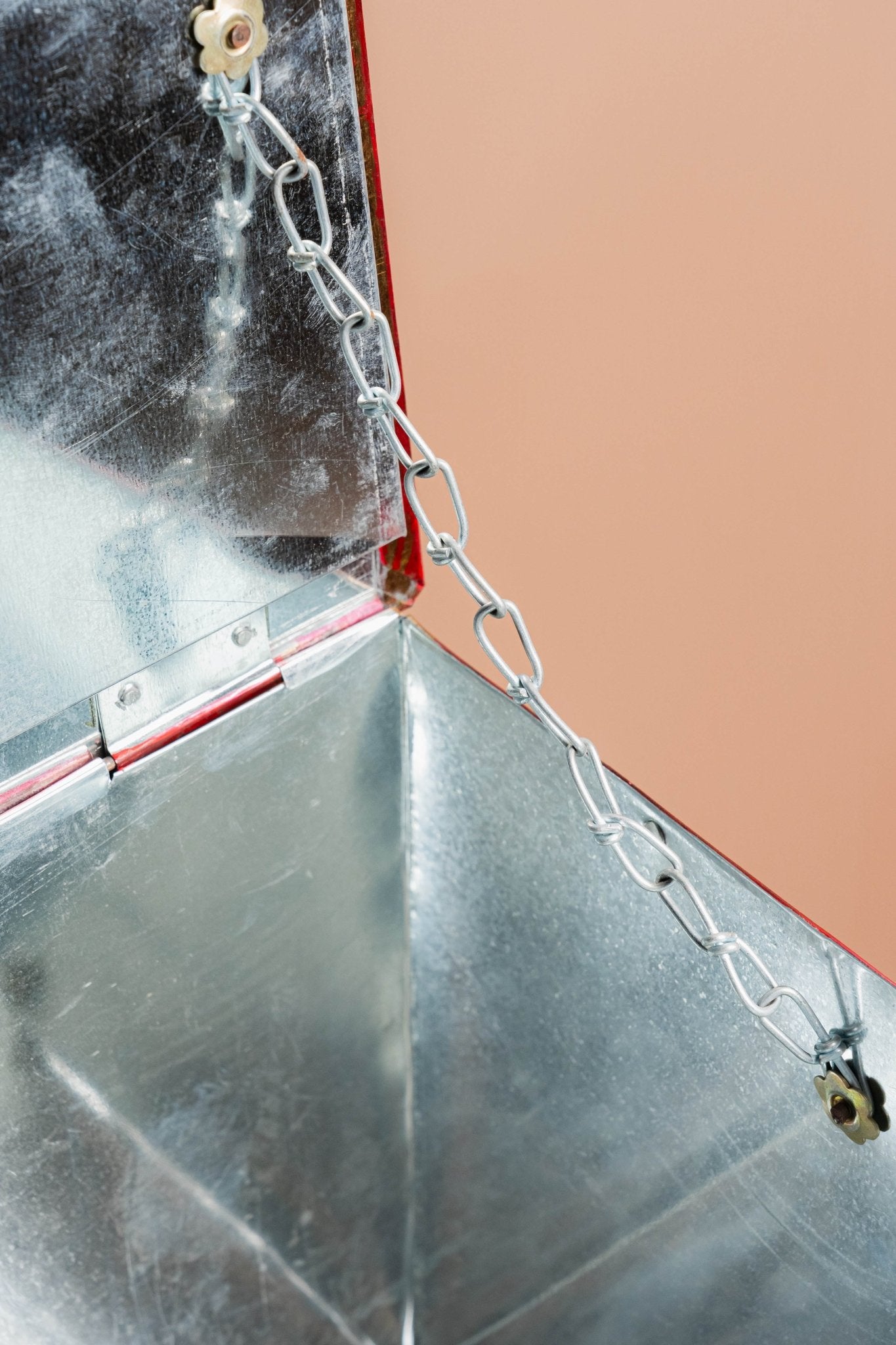 Metallic surface with a chain and mechanical components on a pink background