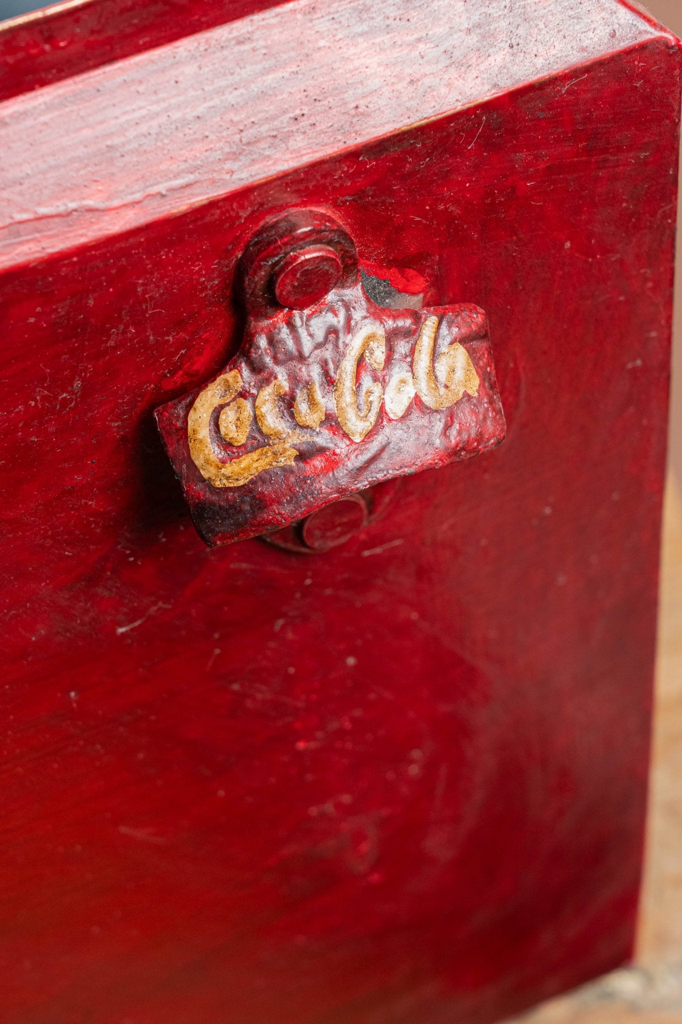 Red metal box with a Coca-Cola logo on a wooden surface