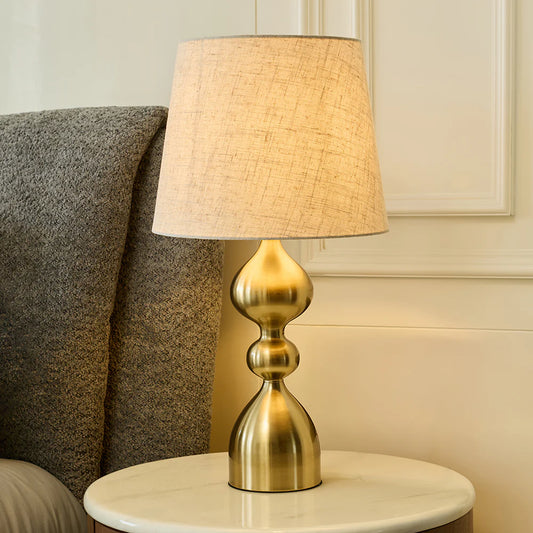 The Alara Table Lamp exudes contemporary elegance with its gracefully sculpted metallic base and soft fabric shade. 