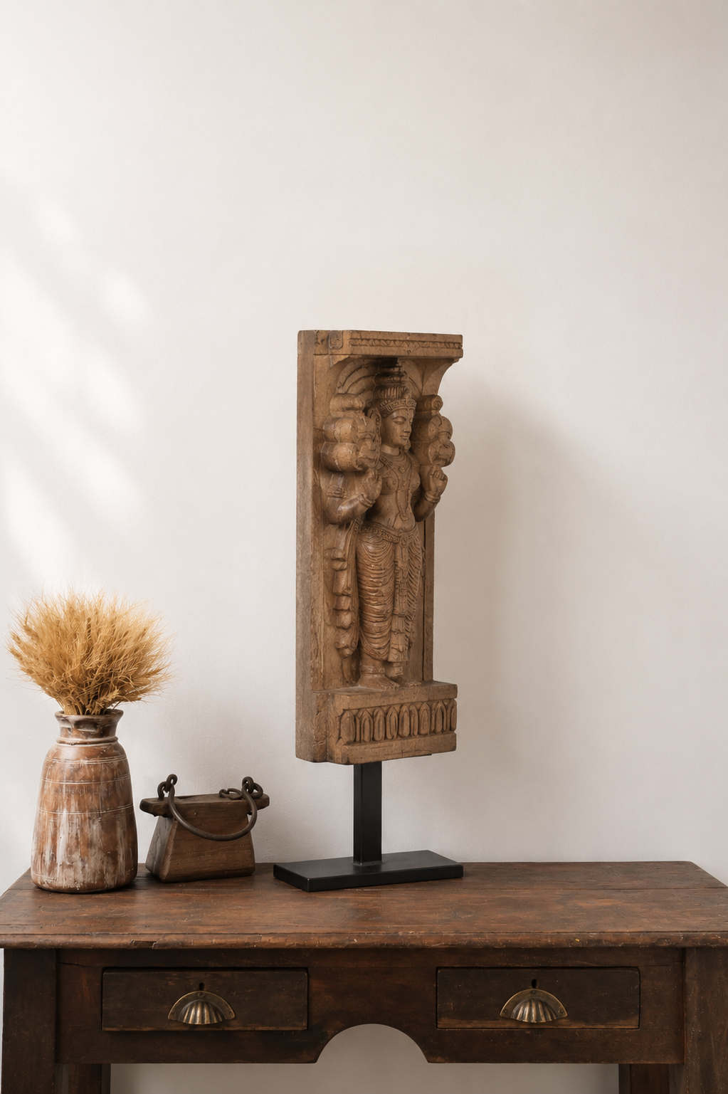Hand-carved reclaimed wood architectural bracket featuring a traditional divine figure, displayed on a black iron stand.
