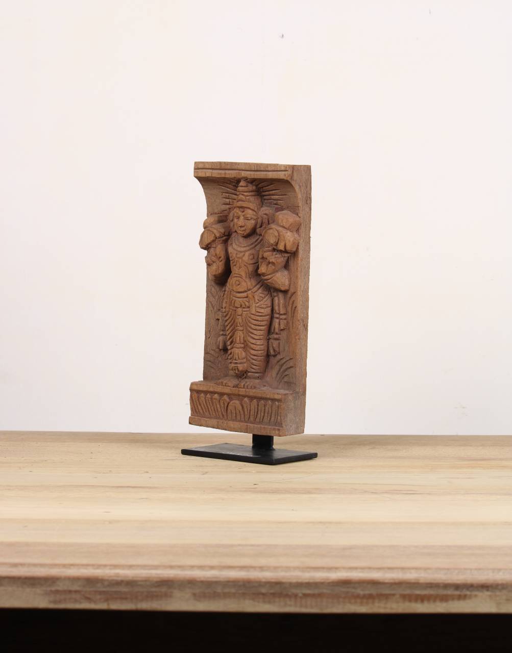 Hand-carved reclaimed wood architectural bracket featuring a traditional divine figure, displayed on a black iron stand.