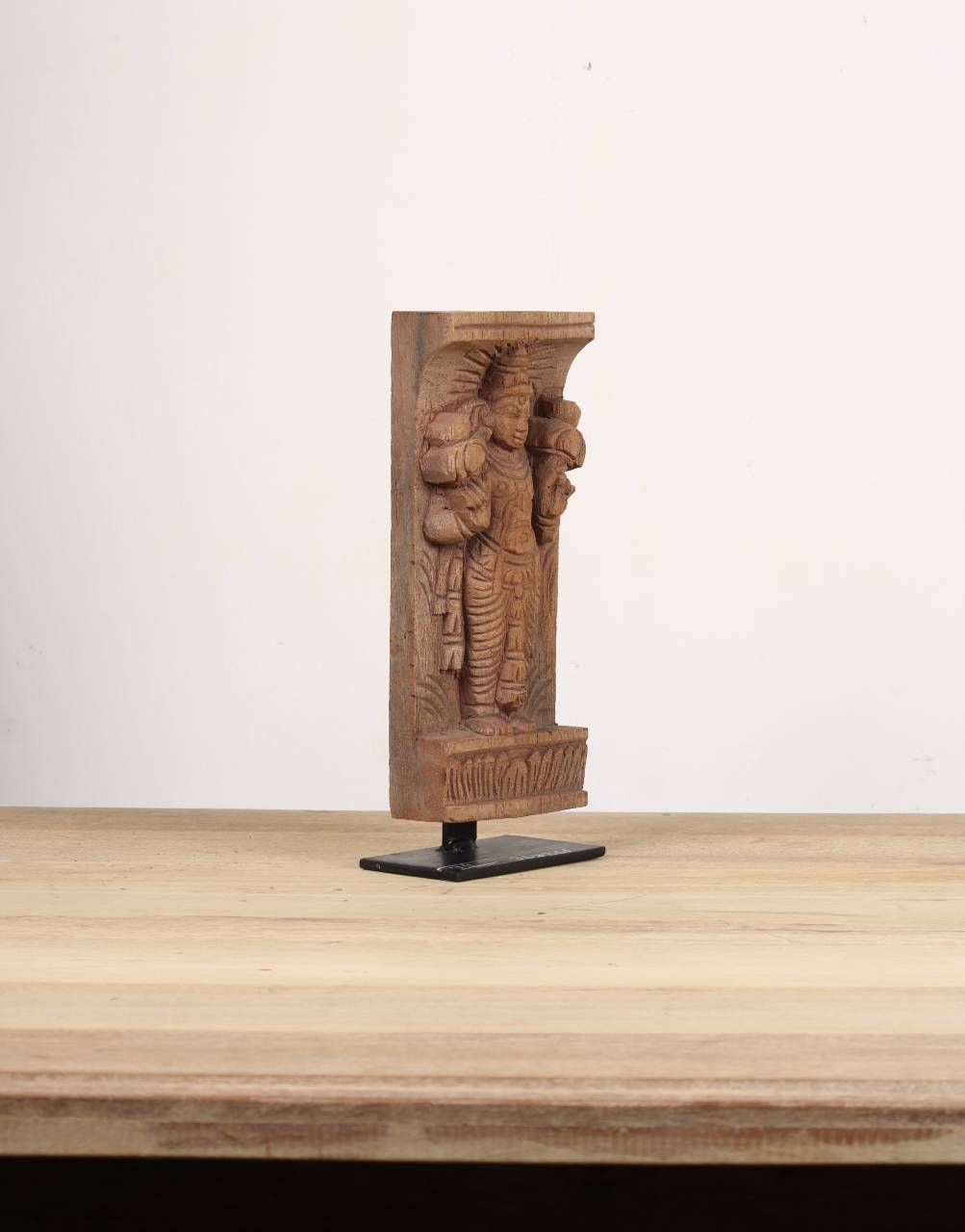 Hand-carved reclaimed wood architectural bracket featuring a traditional divine figure, displayed on a black iron stand.