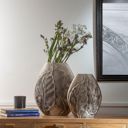  a pair of handcrafted aluminium vases featuring intricately embossed leaf patterns. 