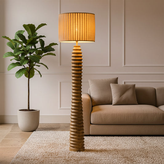 Tall floor lamp with a textured base and striped shade in a room with wooden floors and doors.