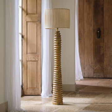 Decorative floor lamp with ribbed design in a room with wooden doors and white curtains.