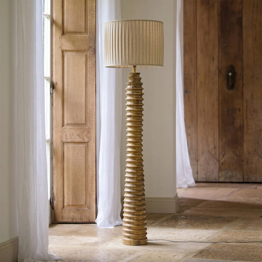 Decorative floor lamp with ribbed design in a room with wooden doors and white curtains.