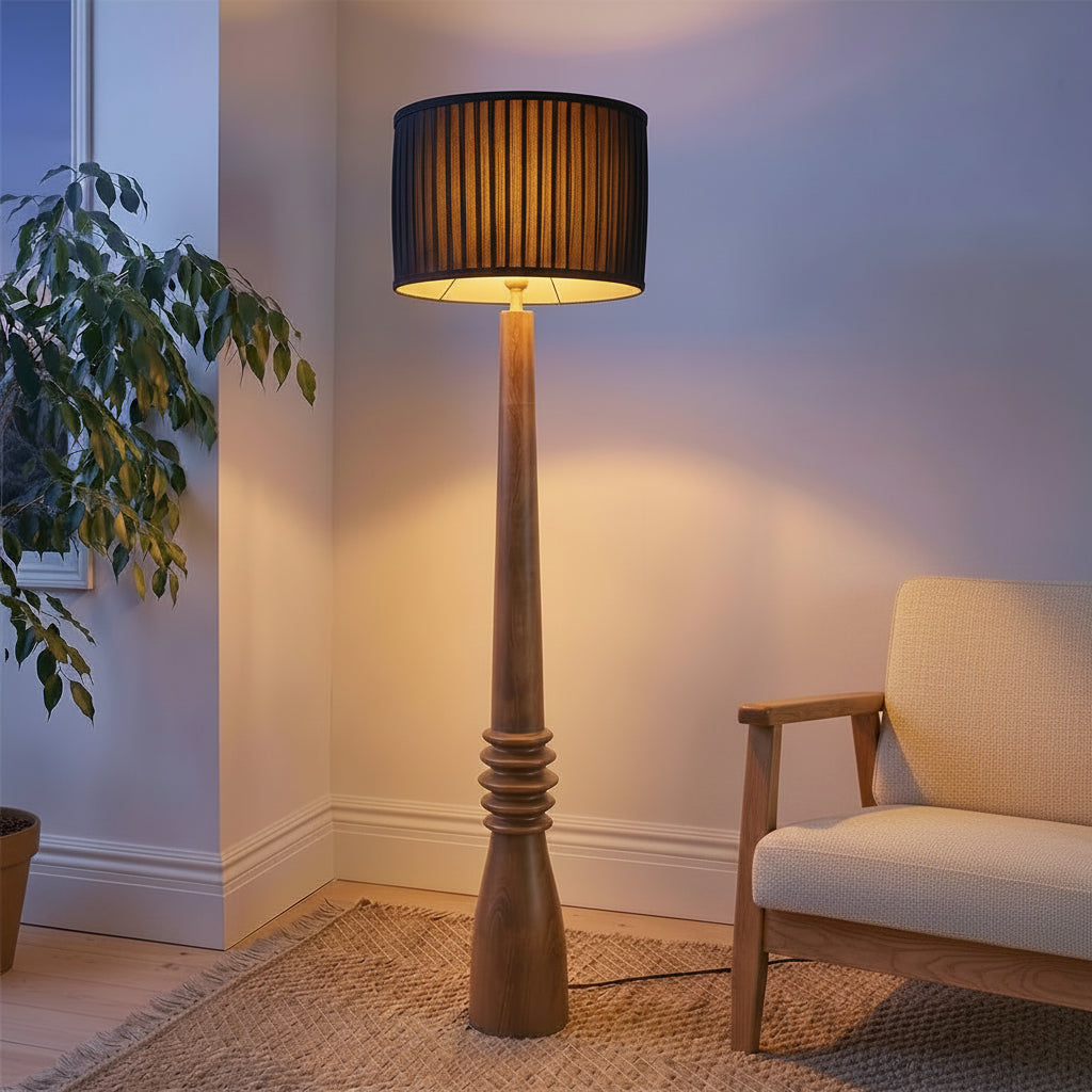 Floor lamp with a black shade in a room with a plant and a chair.