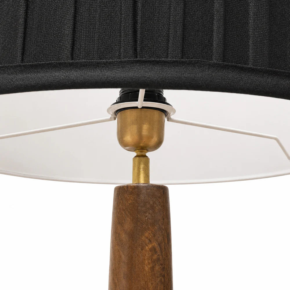 Close-up of a lamp with a black shade, white inner shade, and wooden base.