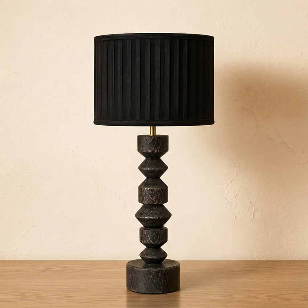 Black table lamp with decorative base on a wooden surface
