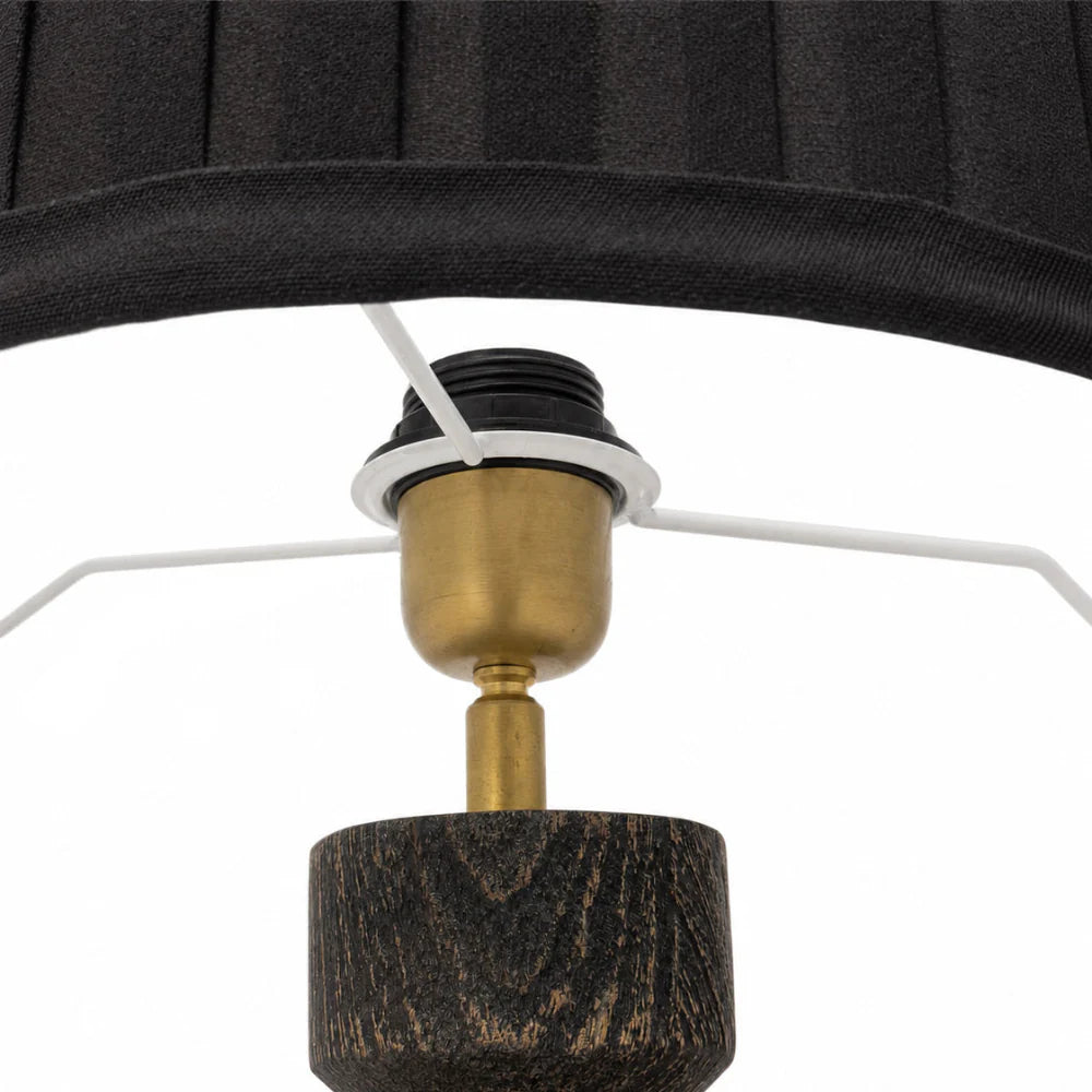 Close-up of a lamp with a black shade, wooden base, and brass fitting on a white background.