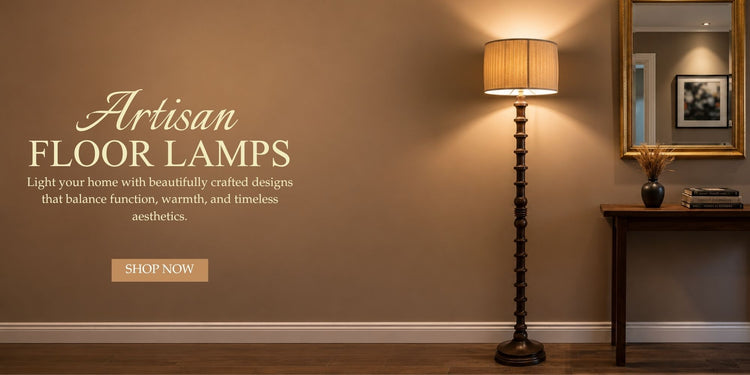 A tall floor lamp with a textured beige drum shade and a dark twisted metal base stands in a styled interior room with a brown wall, wood floor, side table, mirror, and warm lighting.