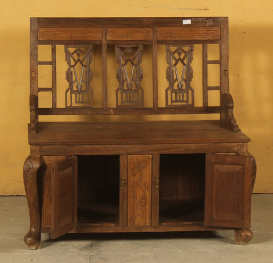 Wooden bench with intricate carvings on a yellow background