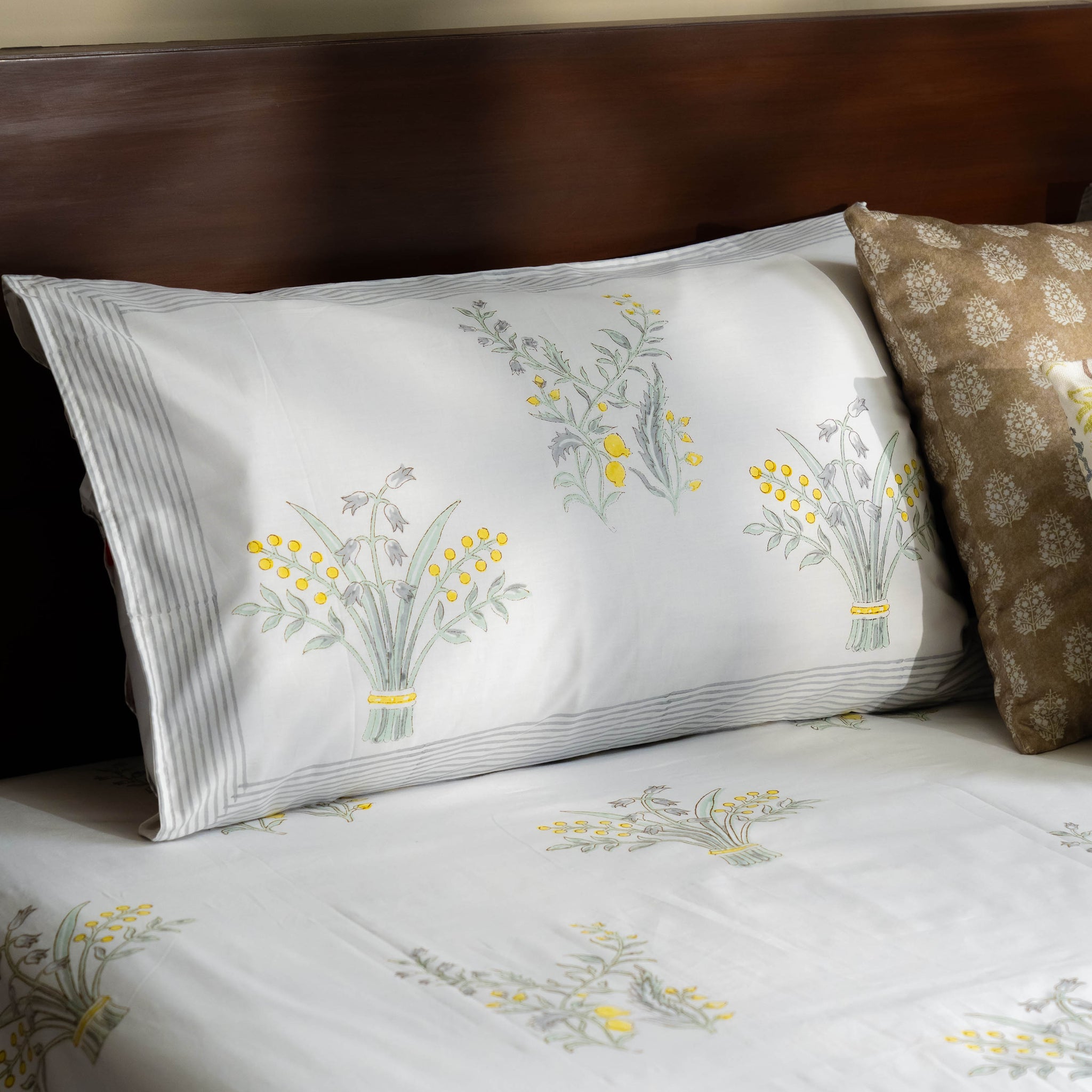 Floral-patterned bed sheets and pillow on a bed with a wooden headboard.