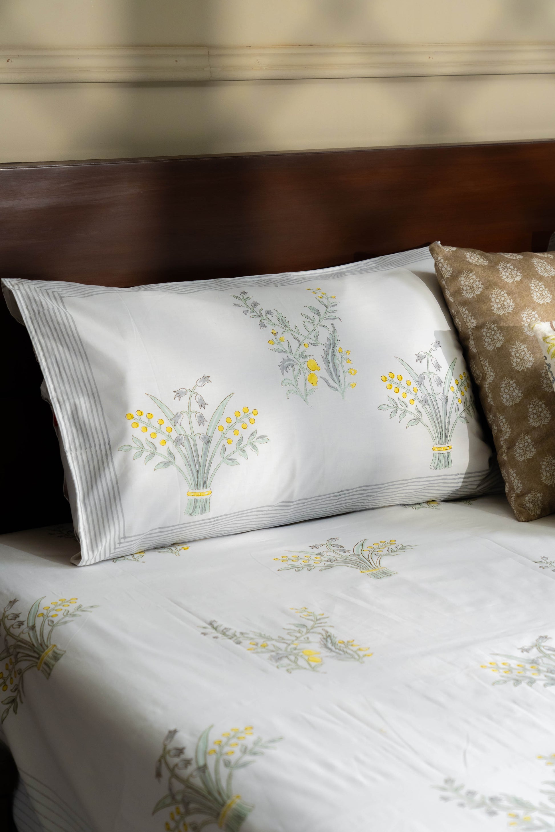 Floral-patterned bed sheets and pillow on a bed with a wooden headboard.