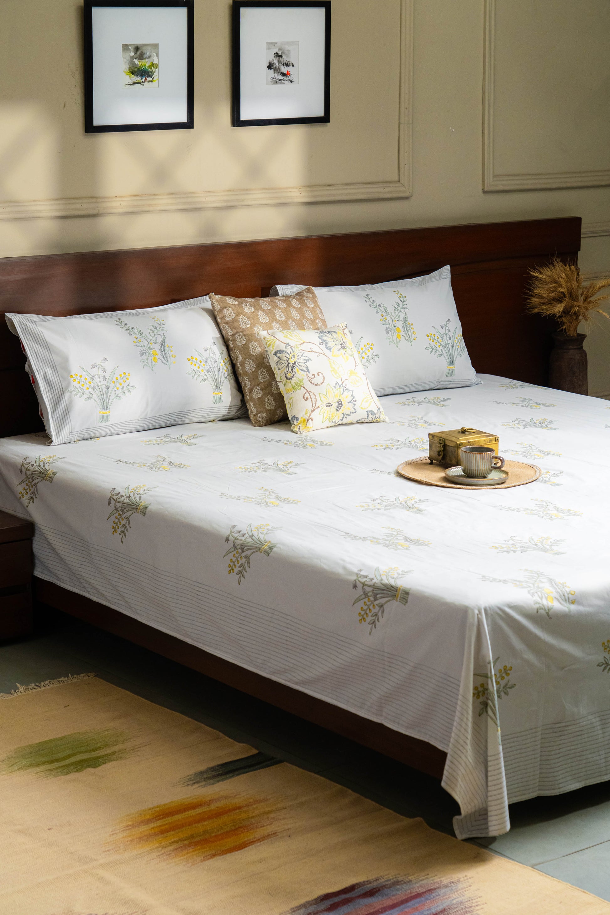 Bedroom with a bed featuring floral bedding and pillows, with a wooden headboard and framed pictures on the wall.