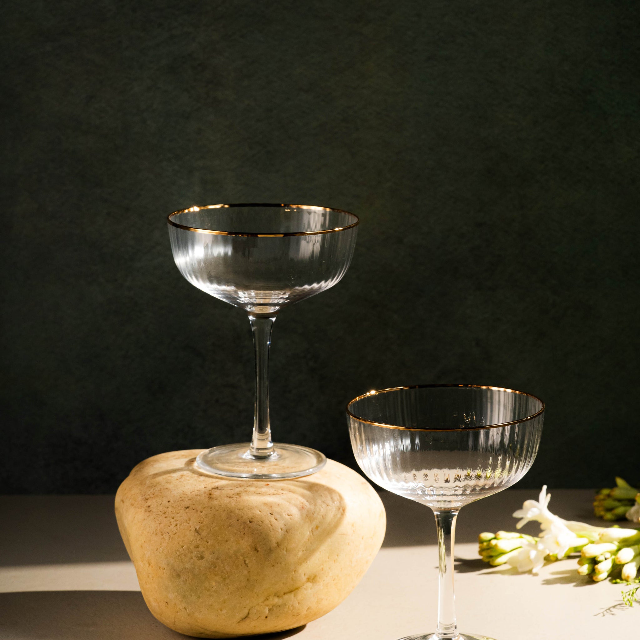 Two glass goblets on a dark surface with a stone block