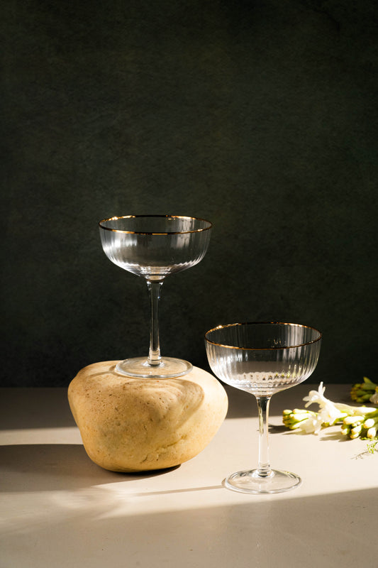 Two glass goblets on a dark surface with a stone block