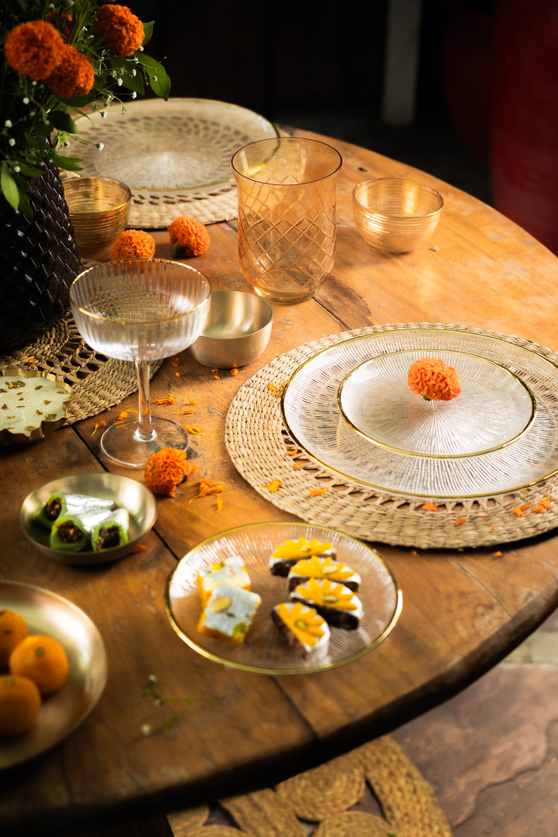 Dining table setting with plates, glasses, and decorative items on a wooden table.