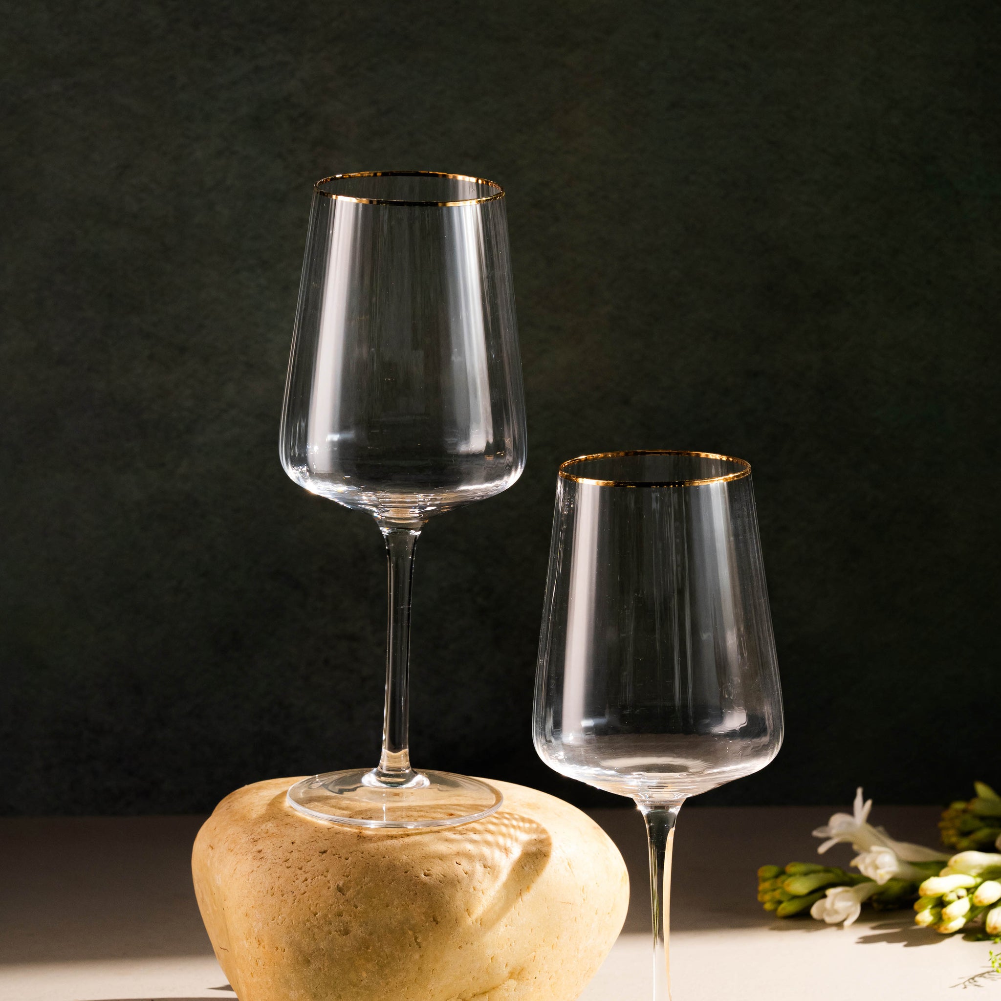 Two wine glasses on a stone surface with a dark background