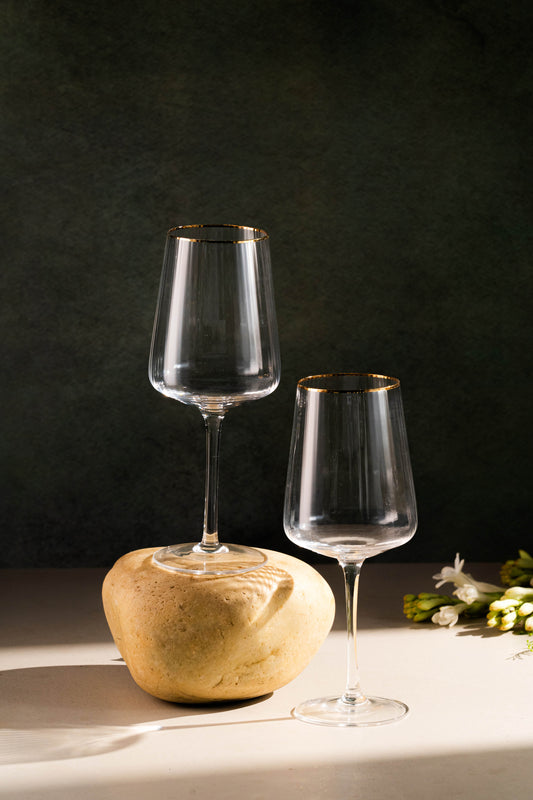 Two wine glasses on a stone surface with a dark background