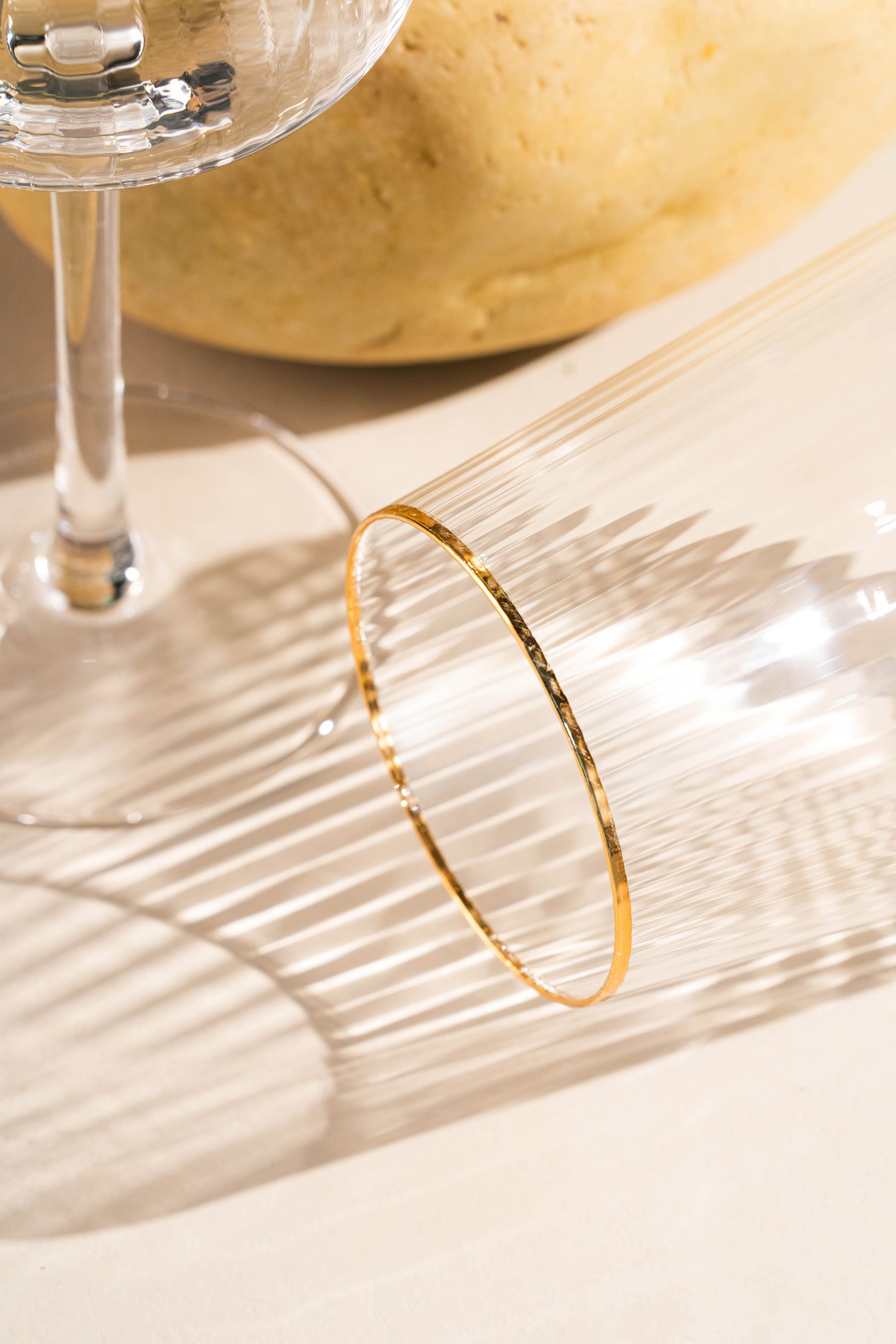 Close-up of a gold bracelet on a glass surface with a blurred background