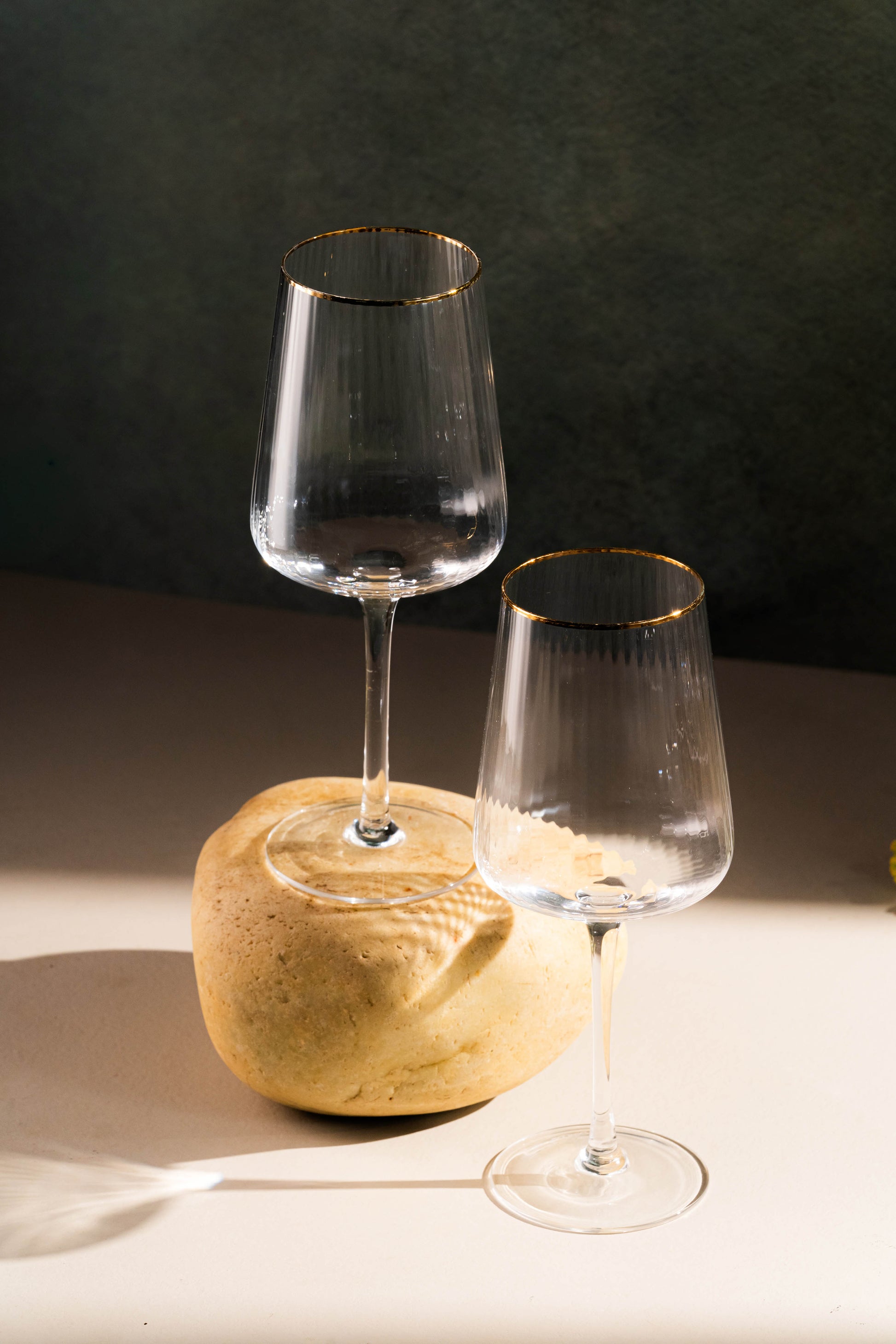 Two wine glasses on a stone surface with a dark background