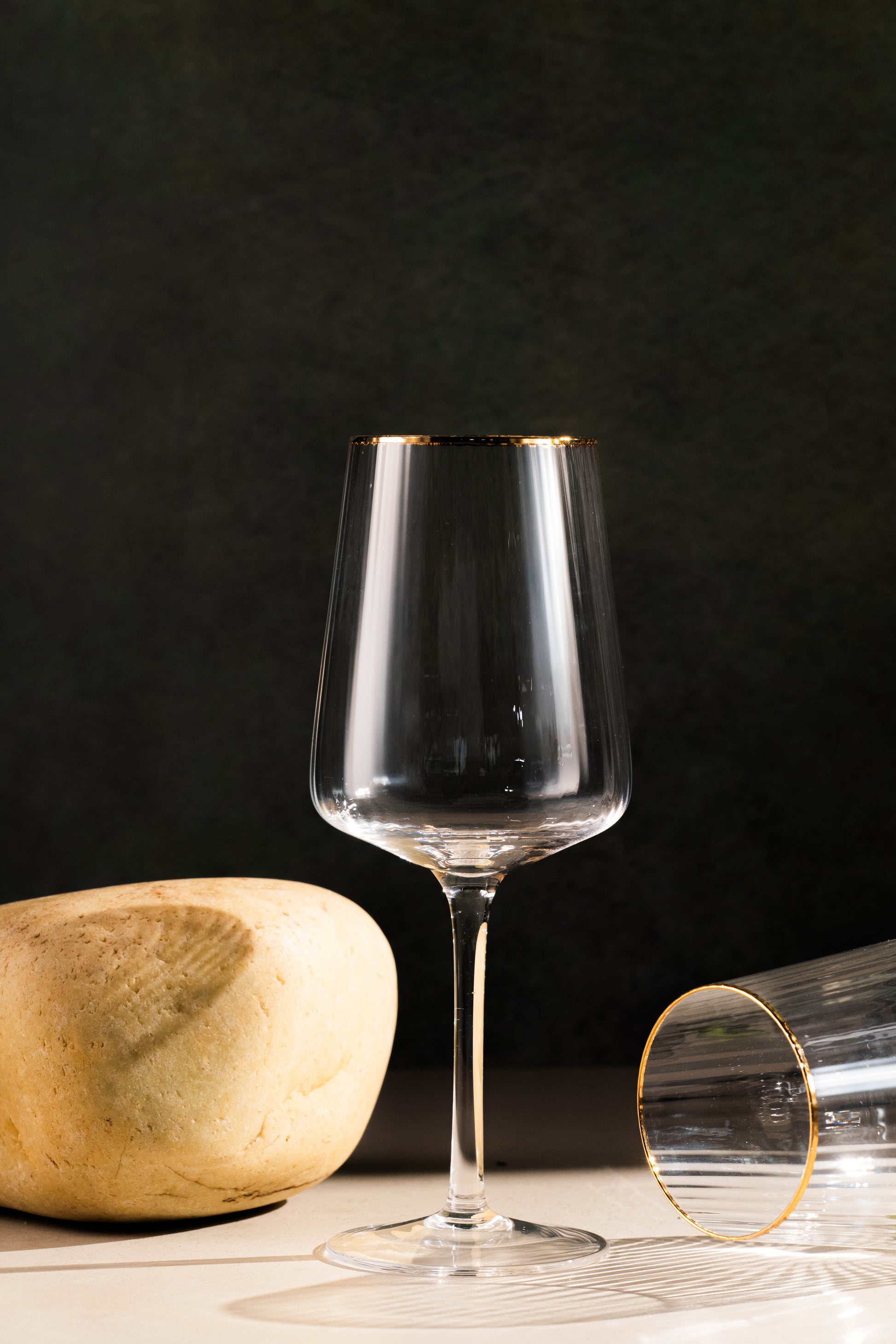 Clear wine glass with gold rim on a dark background