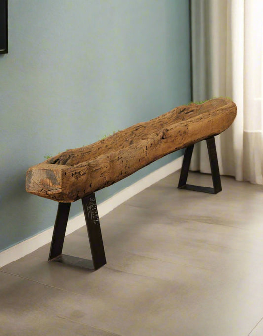 Wooden bench made from a large log with metal legs on a stone floor.