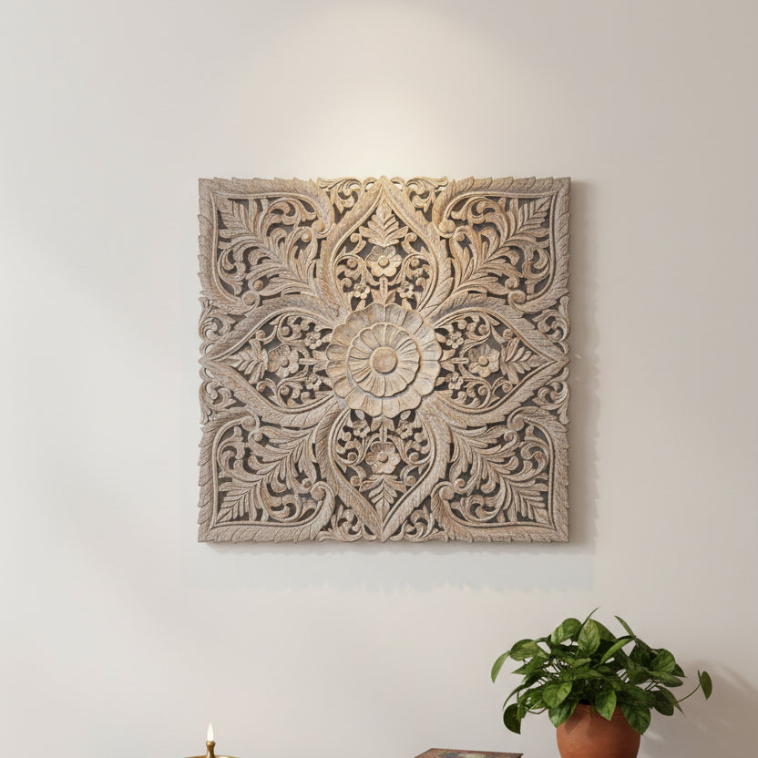 An ornate square carved wooden wall panel with intricate floral and scrollwork patterns, shown leaning against a white wall on a gray concrete floor.