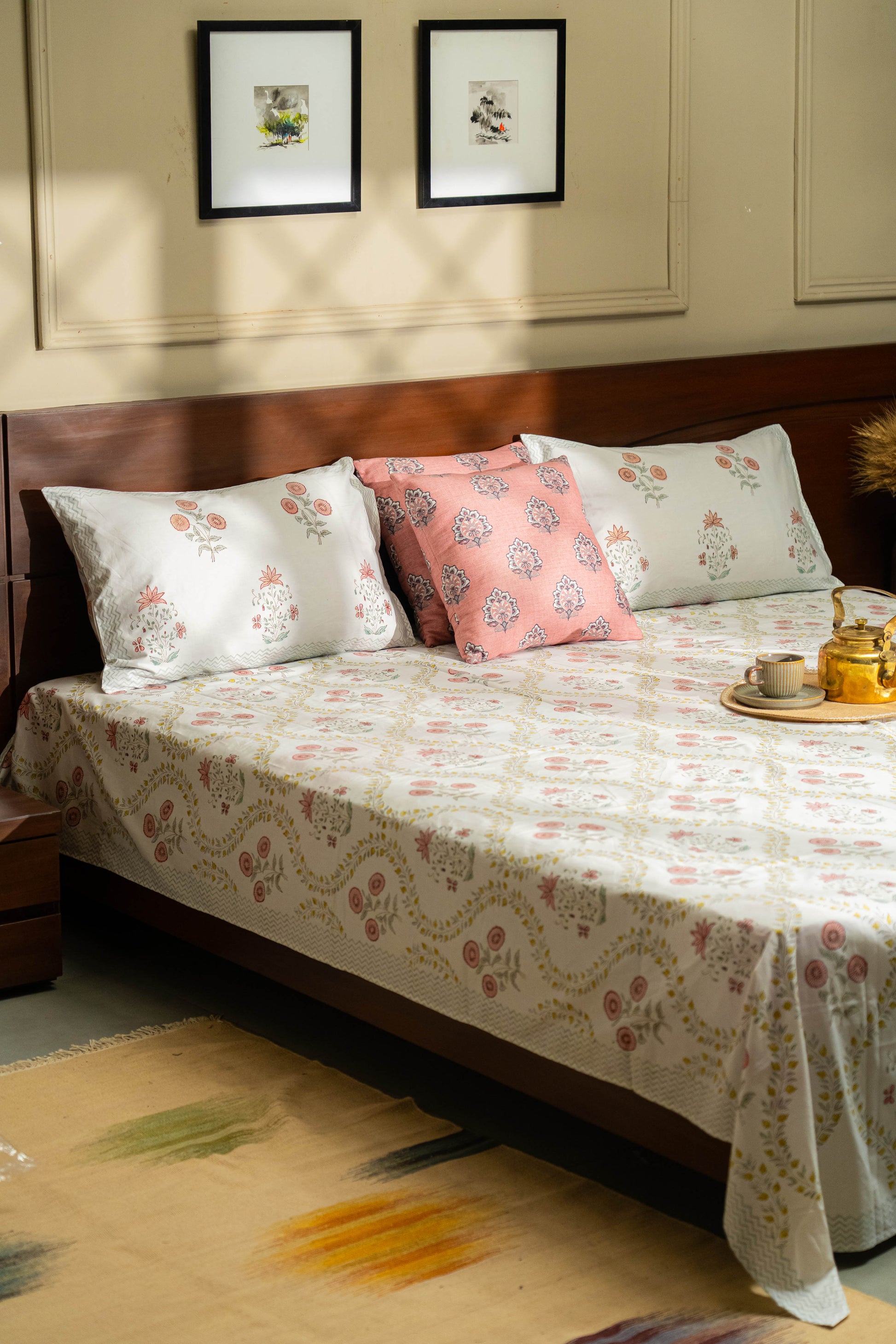 Bed with floral bedding and pillows in a room with framed pictures on the wall.