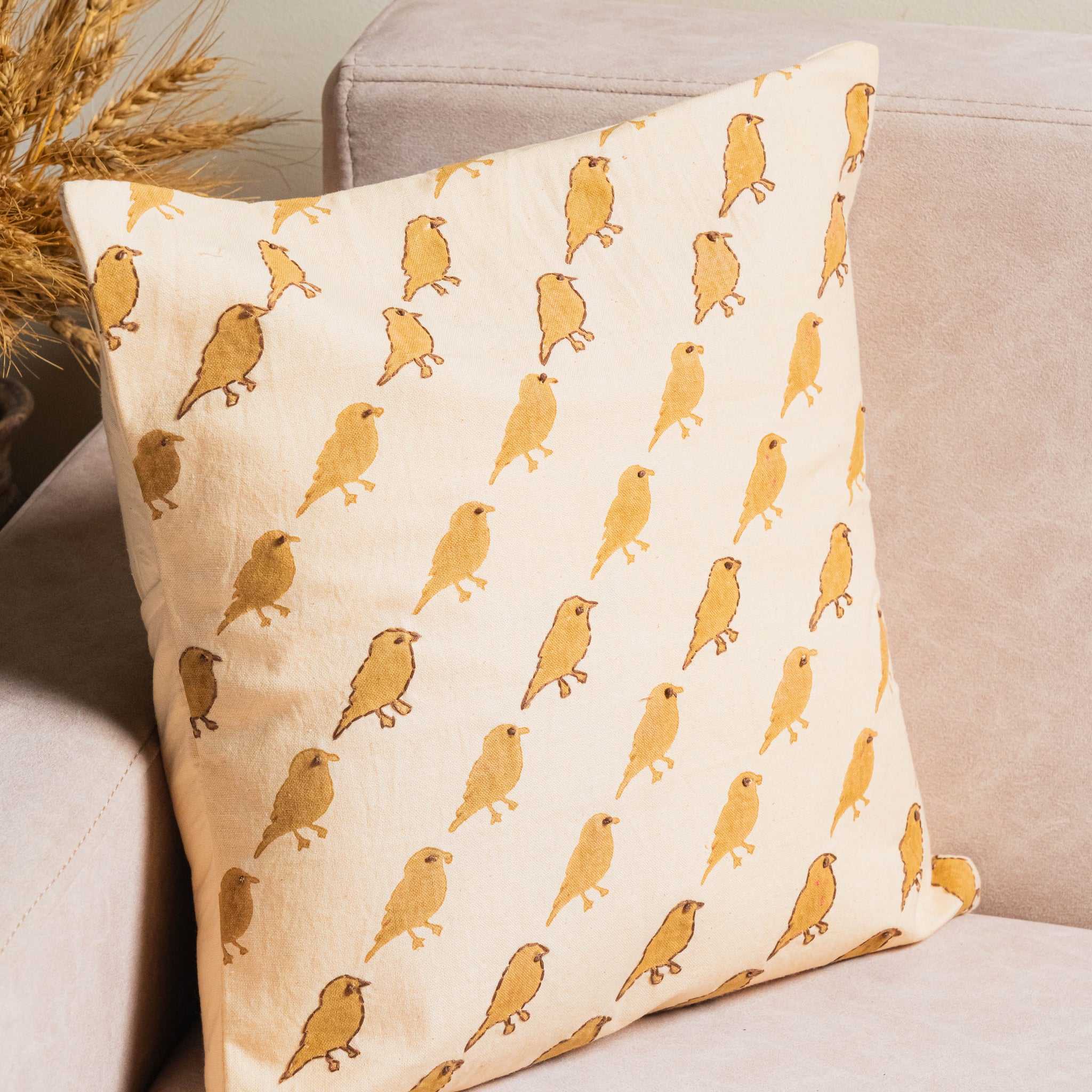 Decorative pillow with bird pattern on a beige couch