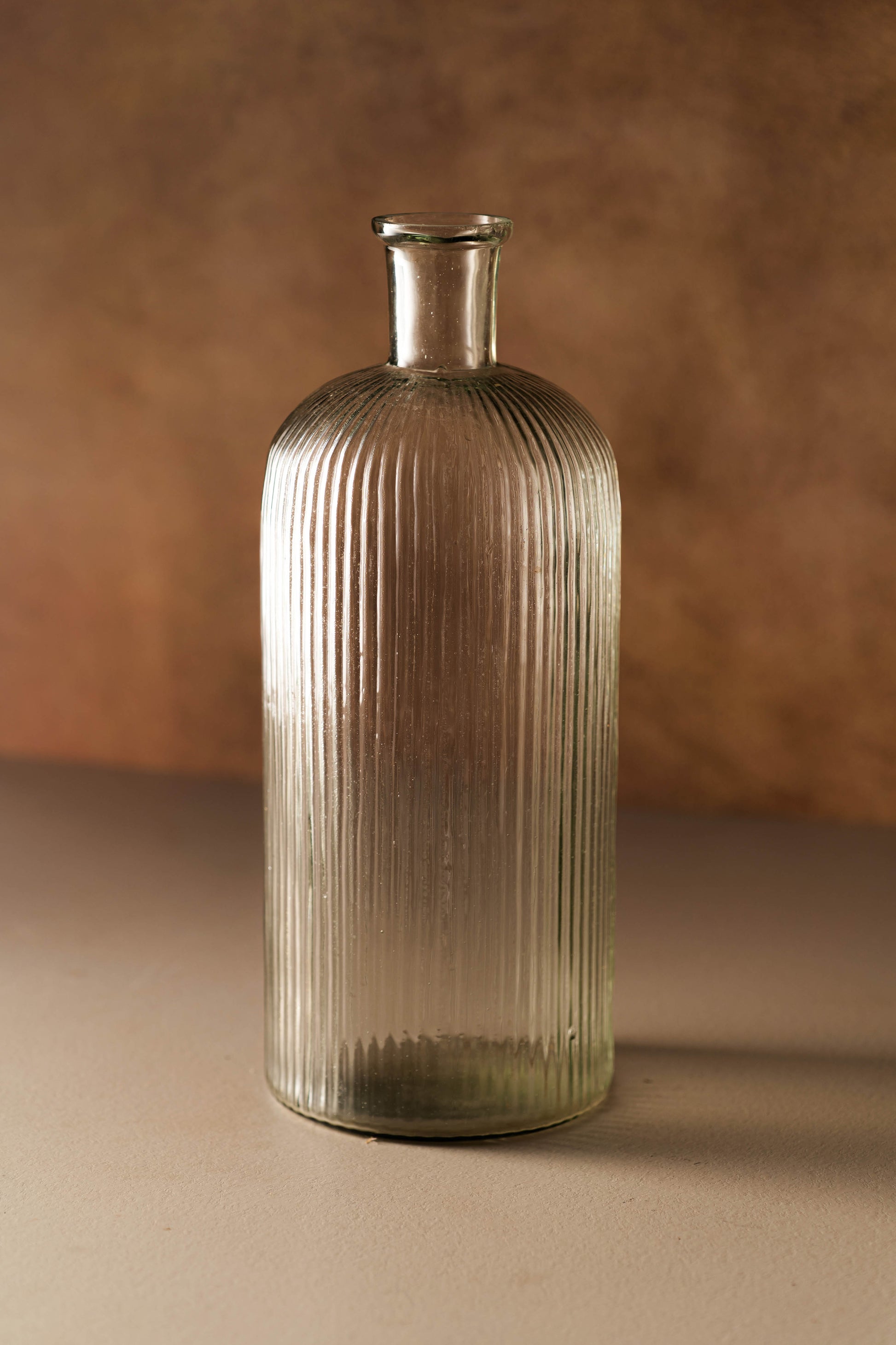 Glass vase with ribbed texture on a brown background