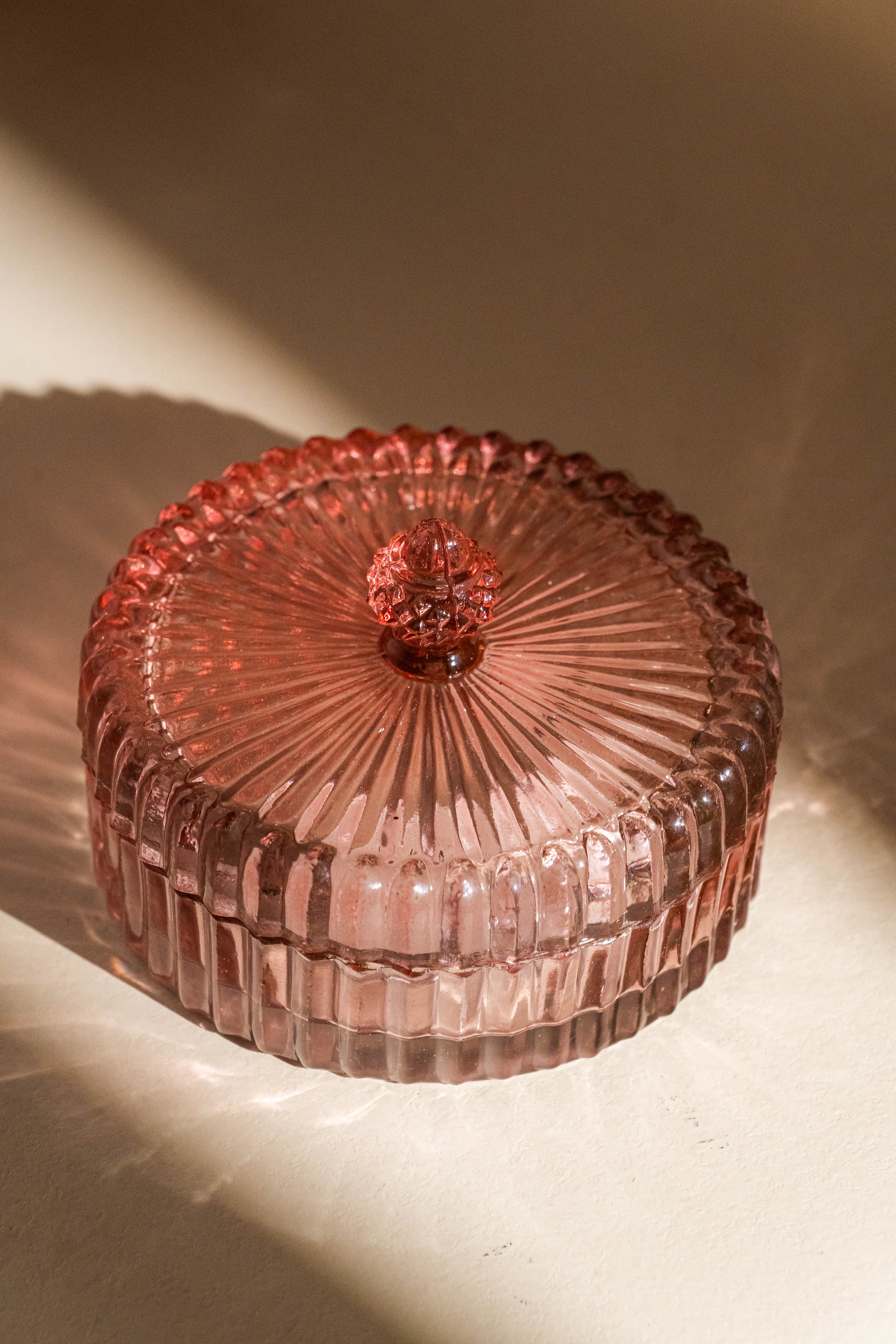 Pink glass dish with a textured surface on a beige background