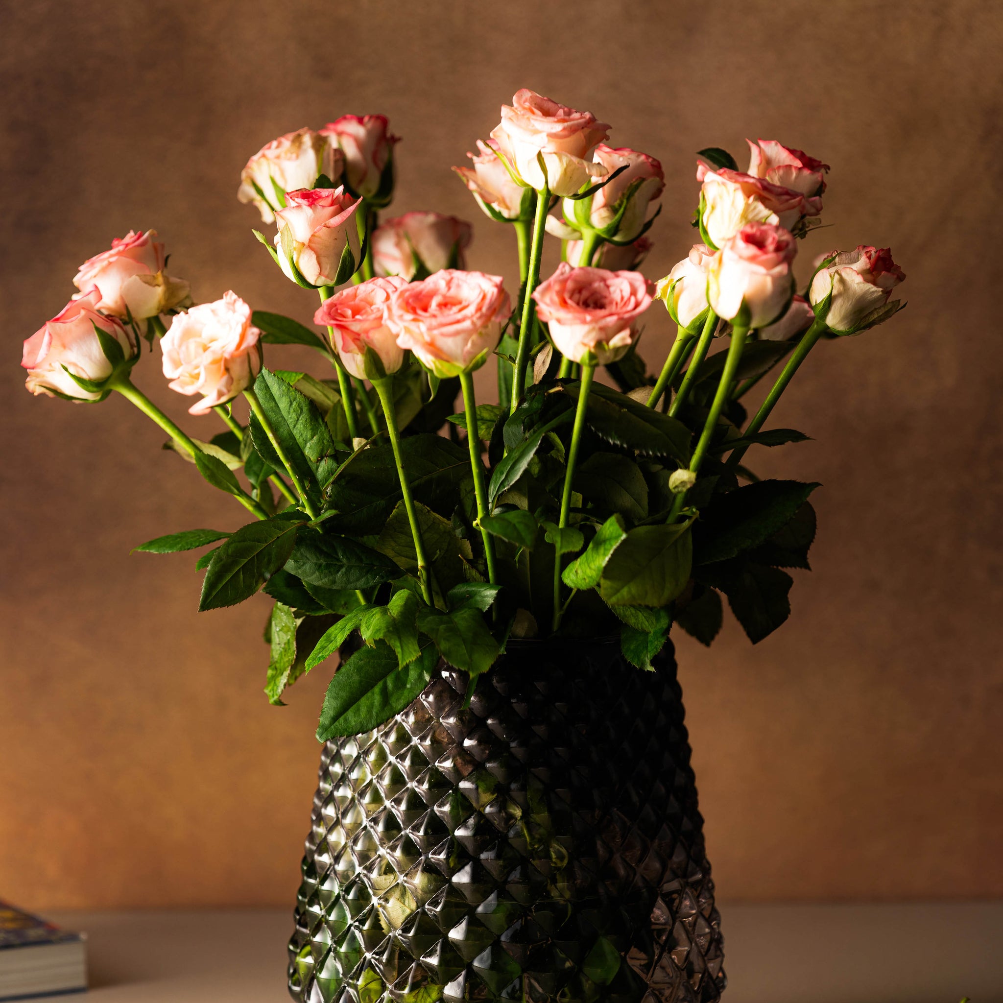 Bouquet of pink roses in a textured vase on a neutral background