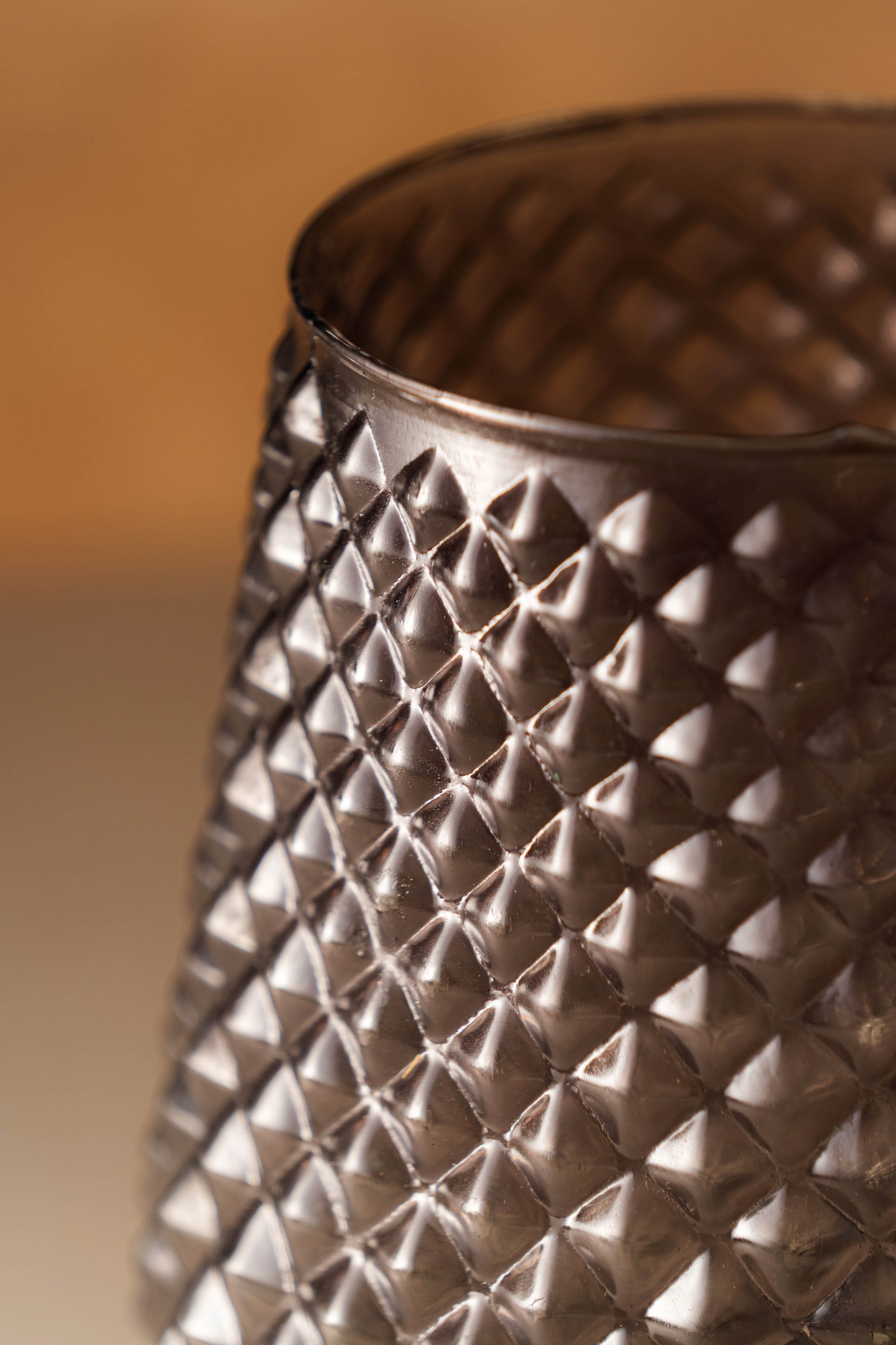 Close-up of a textured metallic object with a diamond pattern on a blurred background
