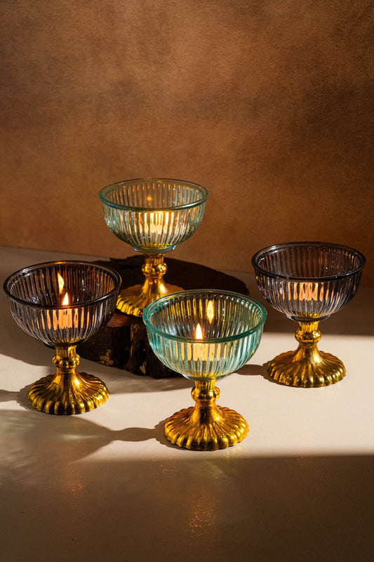 Set of four glass candle holders with gold bases on a brown background