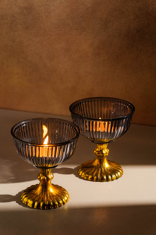 Two decorative glass bowls with gold bases on a neutral background