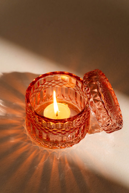 Decorative glass candle holder with a lit candle on a soft background
