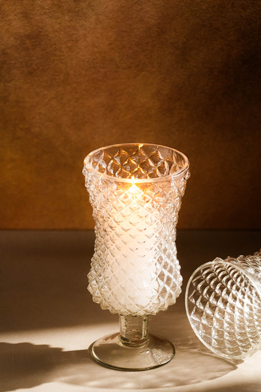 Decorative glass candle holder with a warm glow on a brown background