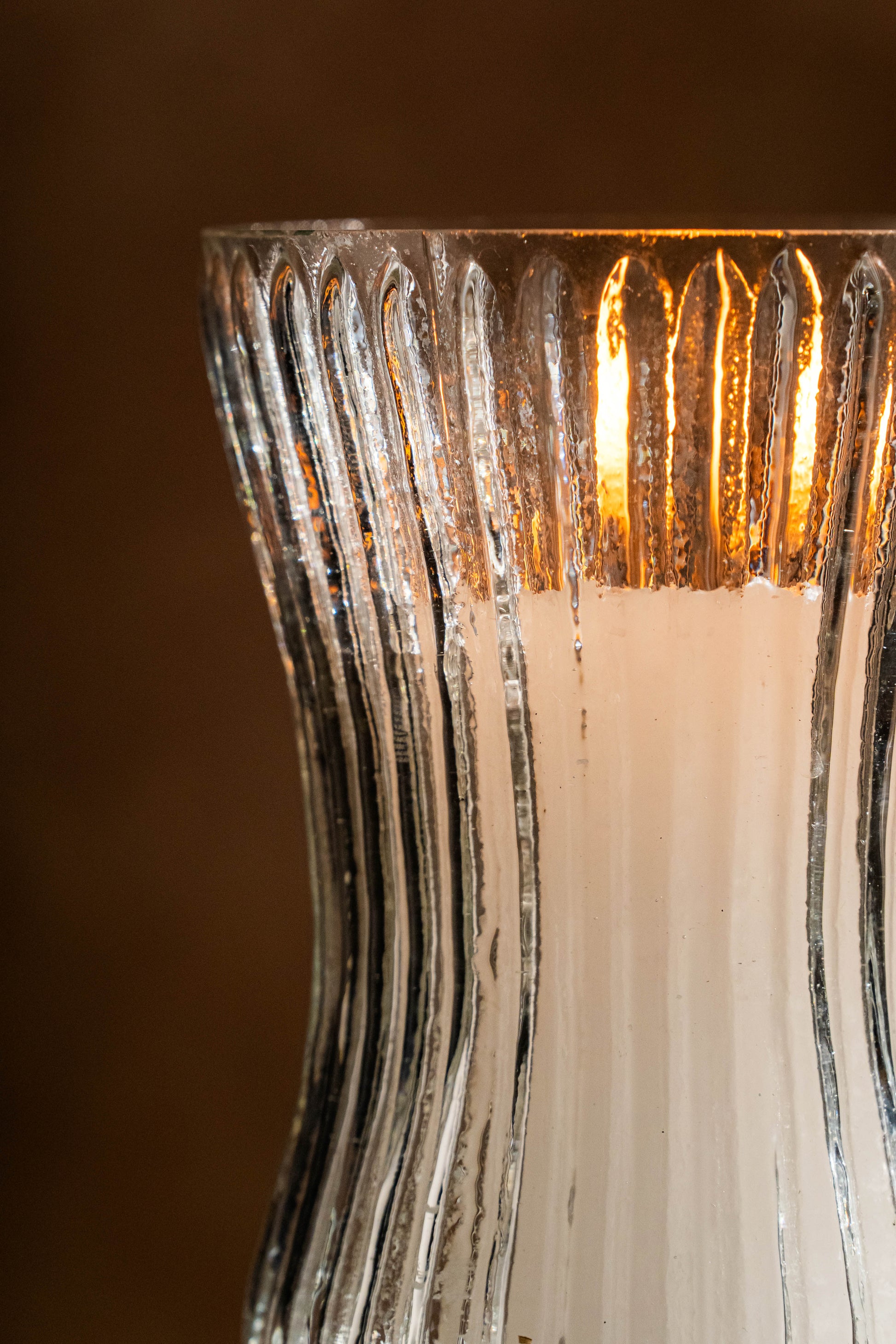 Close-up of a textured glass candle holder with a warm glow.