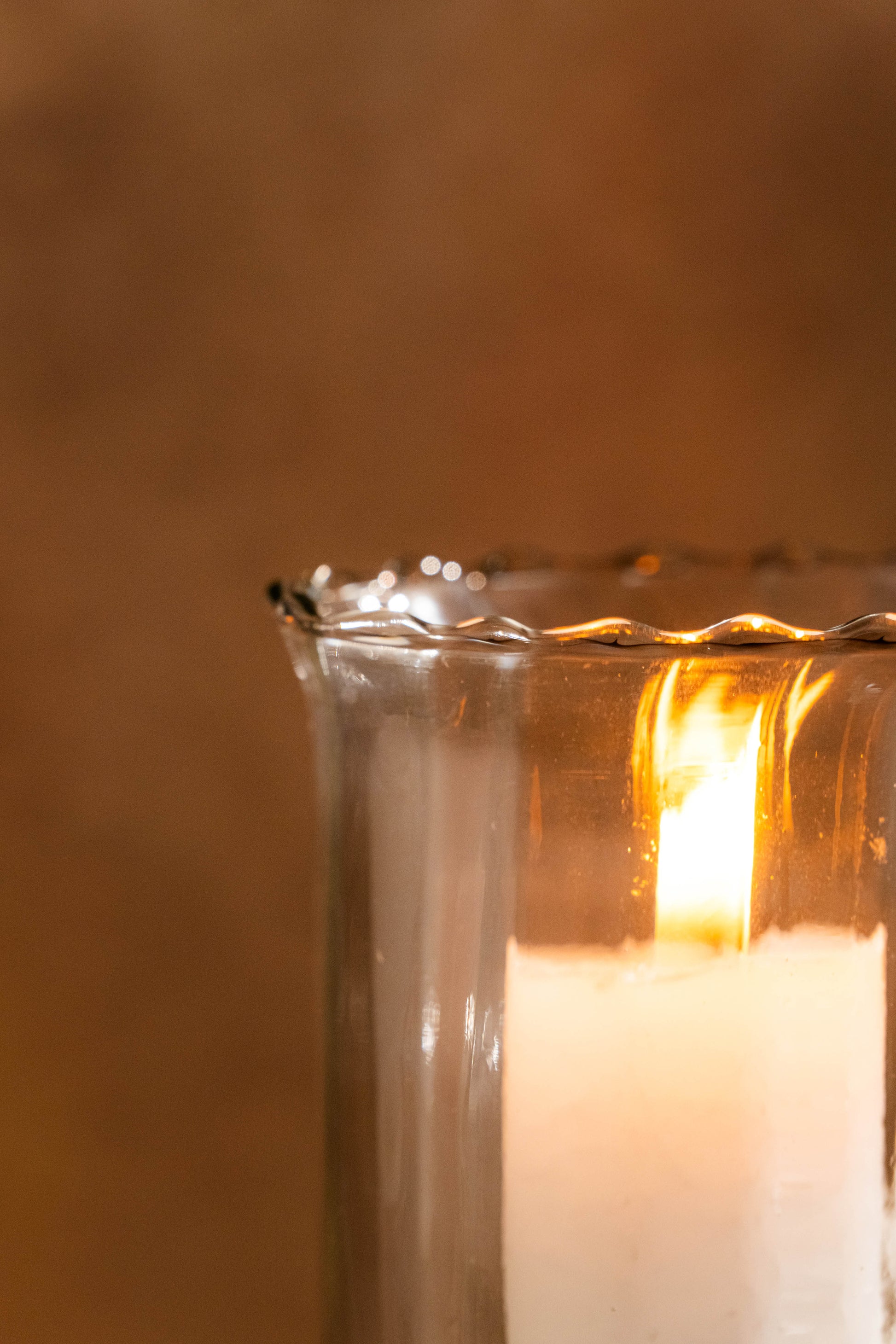 Candle in a glass holder with a warm glow against a blurred background
