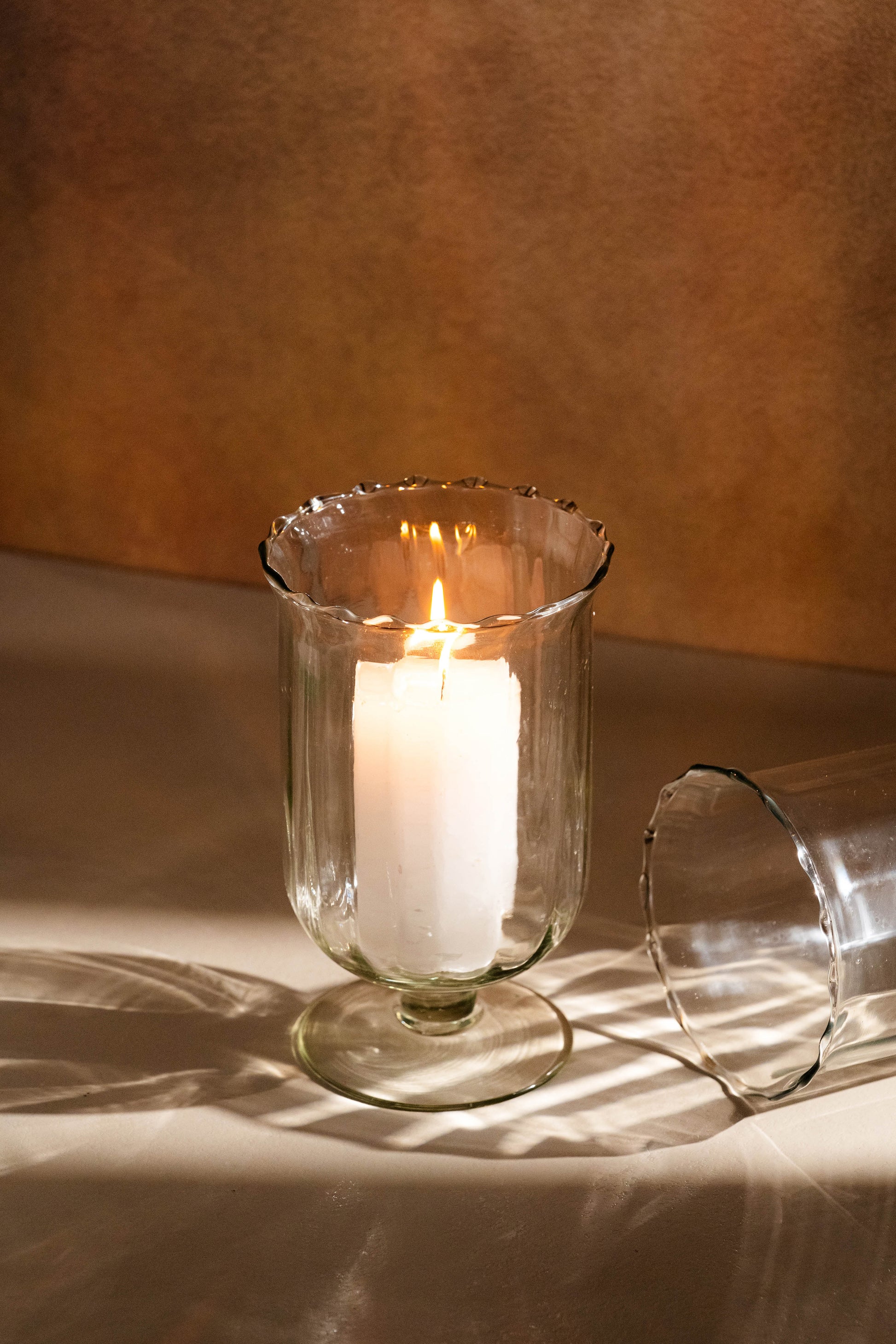 Candle in a glass holder on a textured surface with a warm background