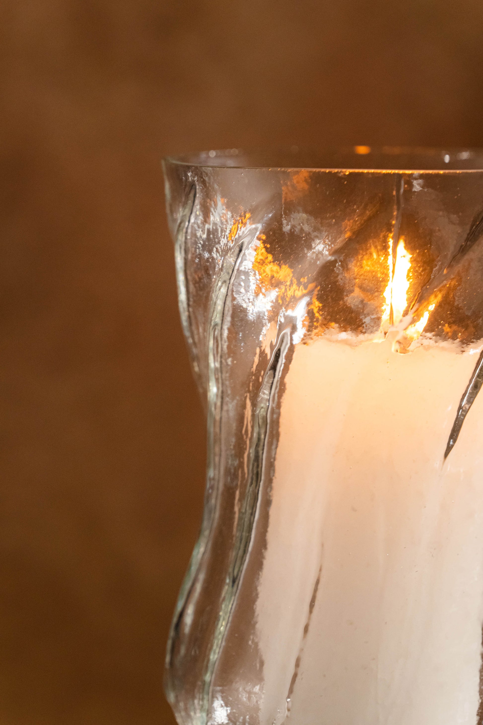 Candle in a glass holder with a textured surface on a blurred background
