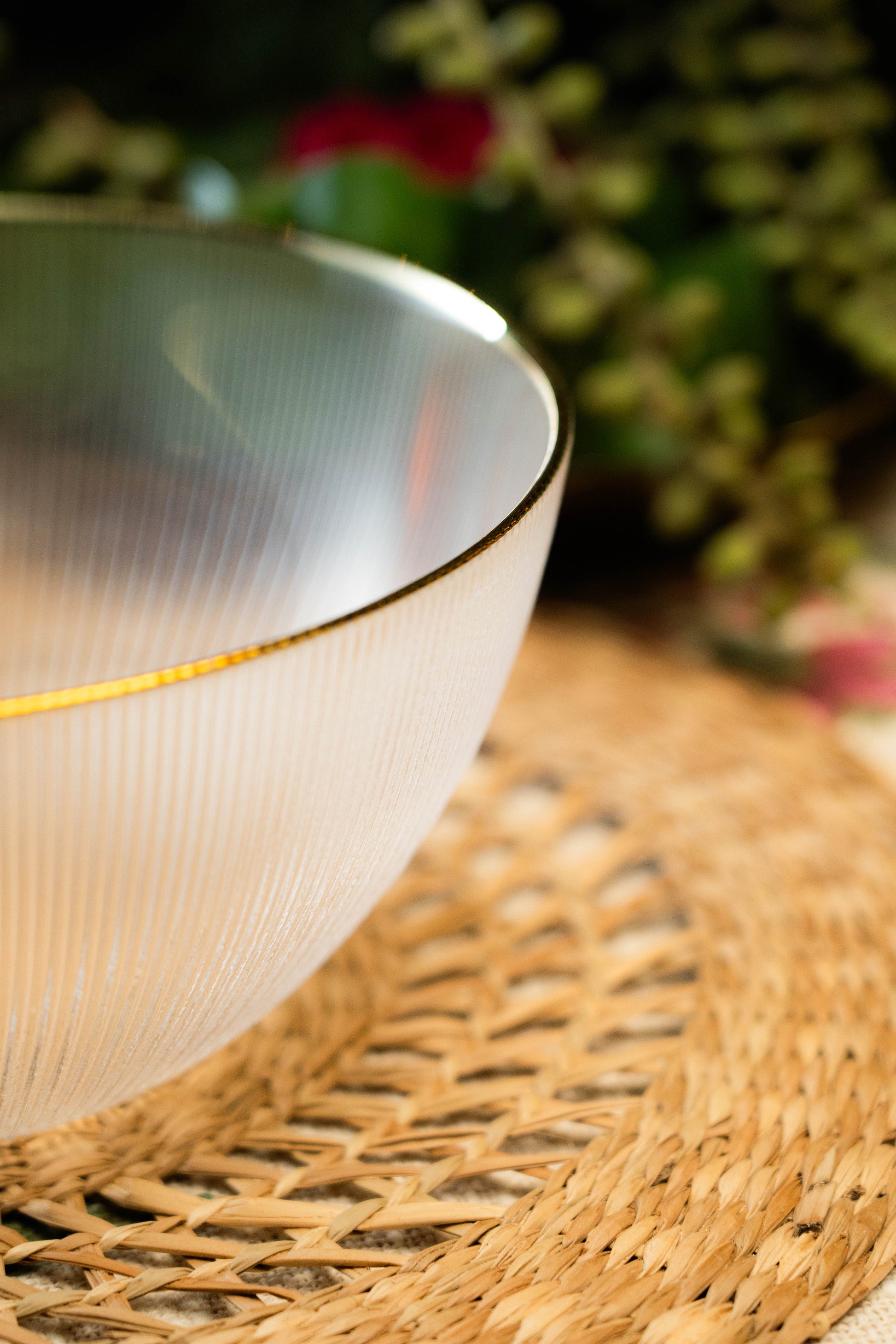 White ceramic bowl with gold rim on a woven mat