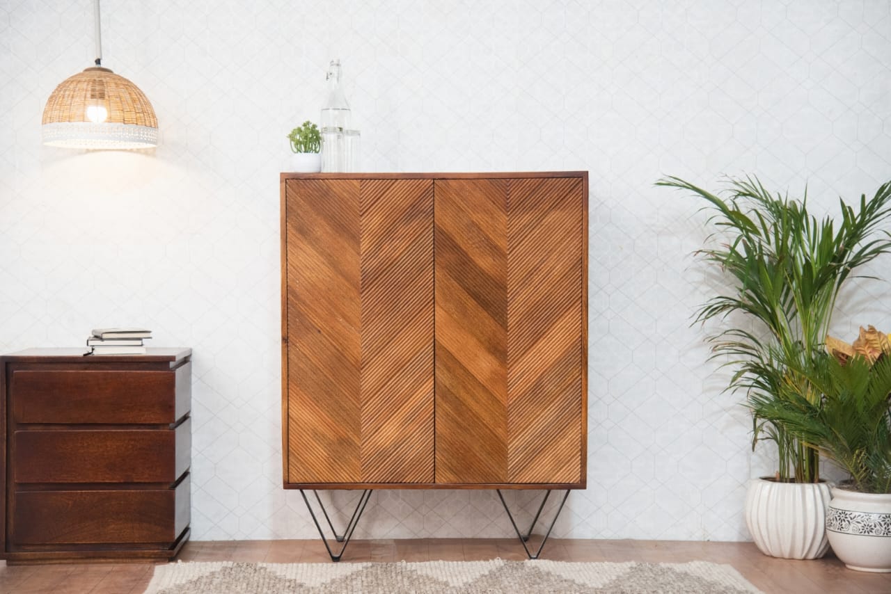 The Golden Crest Bar Cabinet is a statement piece that exudes sophistication and warmth. Its striking chevron-patterned doors, finished in rich golden brown hues, add a touch of modern rustic charm to any space. 