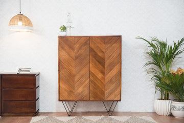 The Golden Crest Bar Cabinet is a statement piece that exudes sophistication and warmth. Its striking chevron-patterned doors, finished in rich golden brown hues, add a touch of modern rustic charm to any space. 