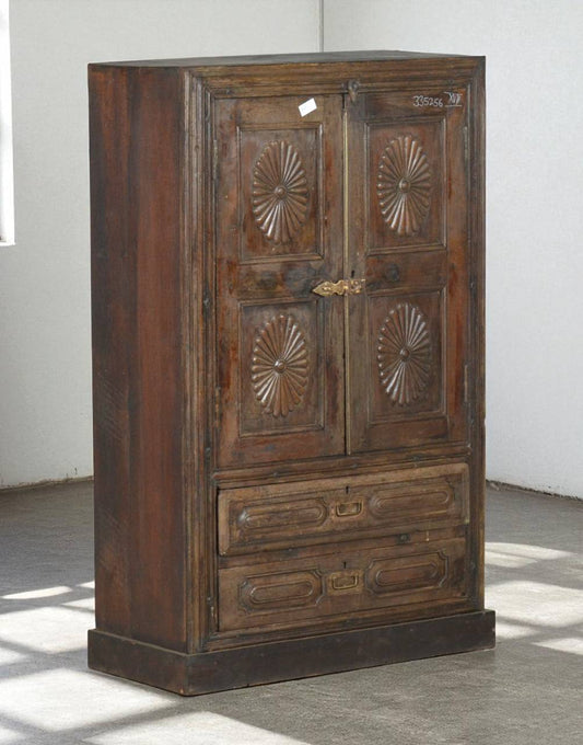 Wooden wardrobe with decorative carvings on a gray floor and white wall.